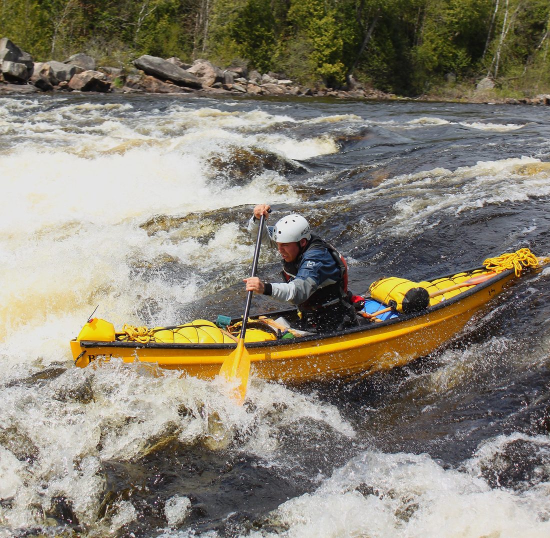 Jean-Sébastien Fontaine paddling a loaded yellow canoe through whitewater on the Rivière du Lièvre